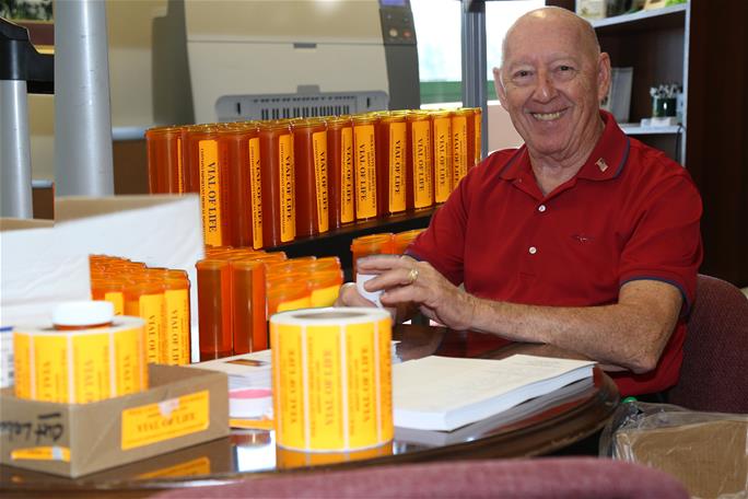 Volunteer with vial of life sitting with many vials